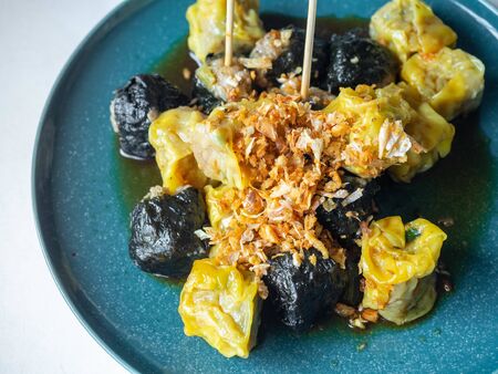 Pork dumplings and dumplings wrapped in seaweed on a round dish topped with fried garlic Increase the aroma of food Topped with salty and sour sauce White backgroundの写真素材