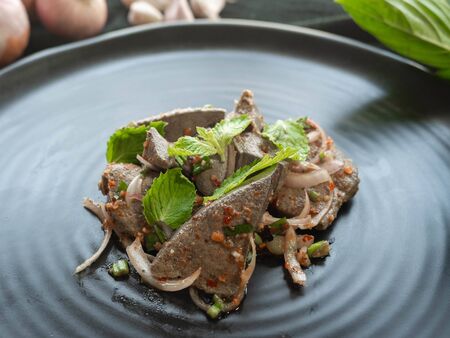 Spicy Pork Liver Salad,Ingredient Onion,Roasted rice,Basil,Pepper,On a black plate,Thai Street Foodの写真素材