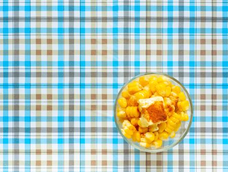 Corn boiled,Butter on top and paprika in glass,Eat with a fork Sweet taste,Blue backgroundの写真素材