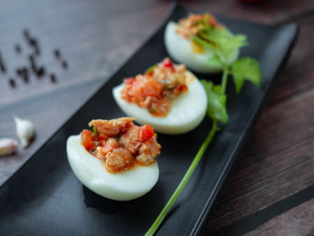 Stuffed Eggs with minced pork
Tomato,Onions,Garlic,Pepper stir well,Place the filling on a boiled egg on a Black plate,Background wood Boiled eggsの写真素材