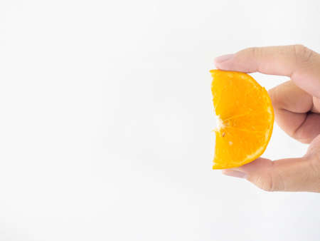 A man's hand holds an orange that has been turned into small halves. With fine stripes of orange...
