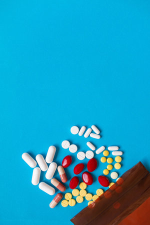 A pill that is poured out of the medicine bag There are many types of drugs used to treat various diseases. Blue backgroundの写真素材