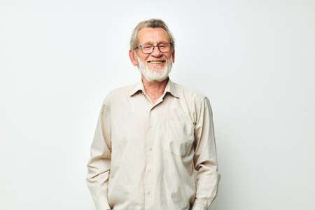 Elderly man posing in studio on gray background and smilingの写真素材