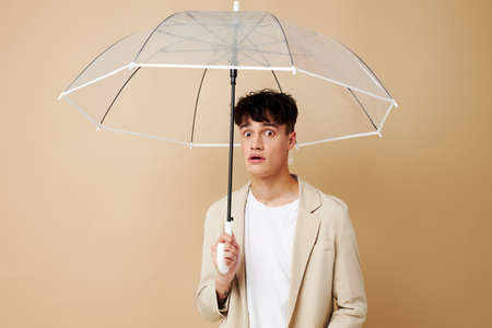 nice guy in a jacket with an open umbrella protection from the rainの写真素材