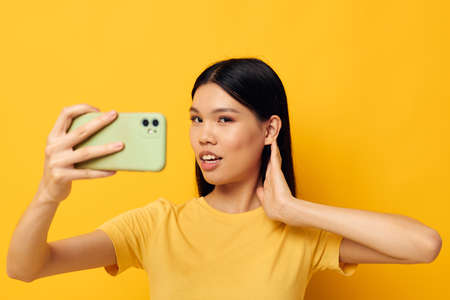woman with a smartphone in hands fun emotions close-up yellow background unalteredの写真素材