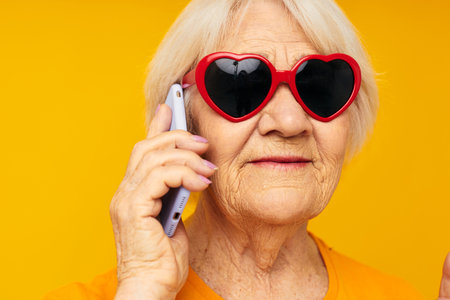 Portrait of an old friendly woman posing face grimace with a phone in hand cropped viewの写真素材
