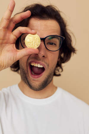 handsome man with glasses gold bitcoin in hands isolated backgroundの写真素材