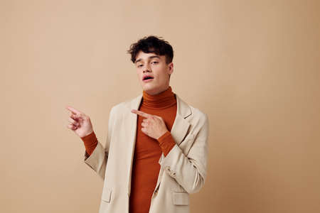 A young man in a beige jacket talking on the phone isolated background unalteredの写真素材