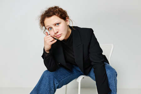 portrait of a young woman sitting on a chair in a black jacket fashion posing Lifestyle unalteredの写真素材