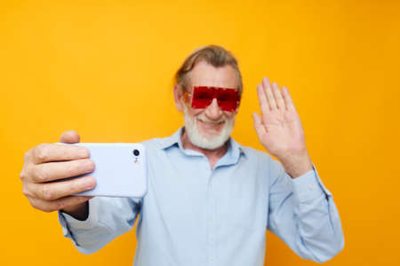 Portrait elderly man blue shirts with glasses takes a selfie unaltered