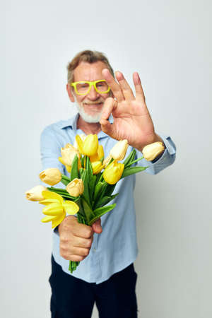 Portrait of happy senior man a bouquet of flowers with glasses as a gift unalteredの写真素材