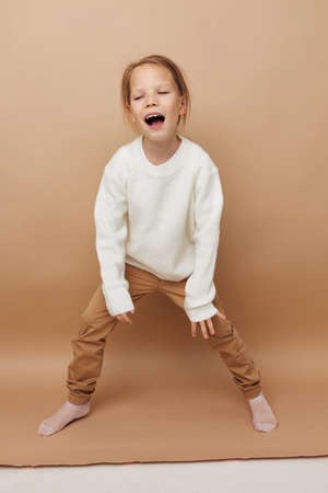 Portrait of happy smiling child girl in white sweater posing hand gestures Lifestyle unalteredの写真素材