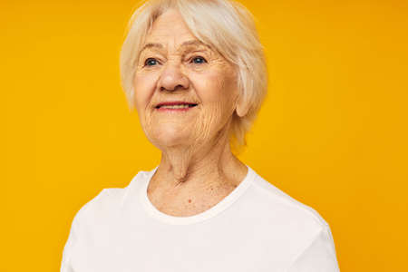 Photo of retired old lady in white t-shirt posing fun yellow backgroundの写真素材
