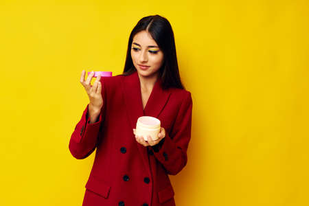 portrait pretty woman red jacket cosmetics skin care yellow background unalteredの写真素材