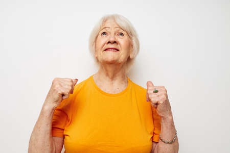 Portrait of an old friendly woman in a yellow t-shirt posing cropped viewの写真素材