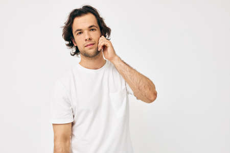man in a white T-shirt hand gesture light backgroundの写真素材