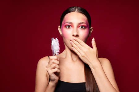 pretty woman pink face makeup posing attractive look with a comb close-up unaltered