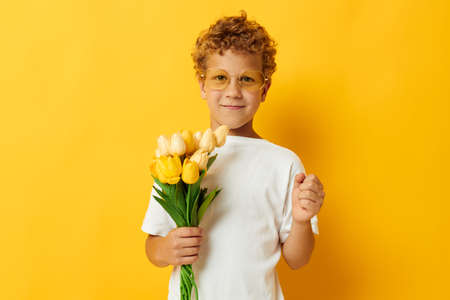 Photo portrait curly little boy with yellow flowers posing childhood fun isolated background...