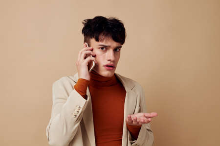 portrait of a young man mobile phone in the hands of communication in a suit fashion light...