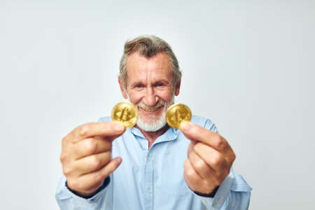 Senior grey-haired man cryptocurrency bitcoin face close up investment light background