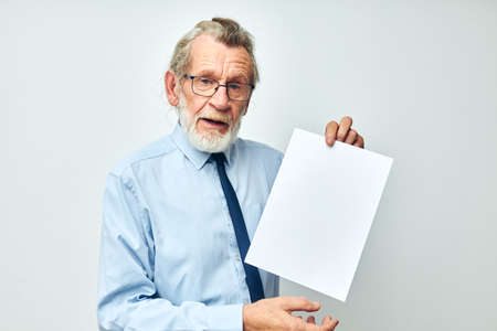 old man in a shirt with a tie copy-space sheet of paper light background