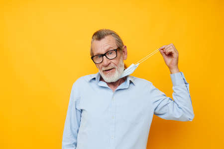 Portrait of happy senior man with glasses safety medical mask posing unalteredの写真素材