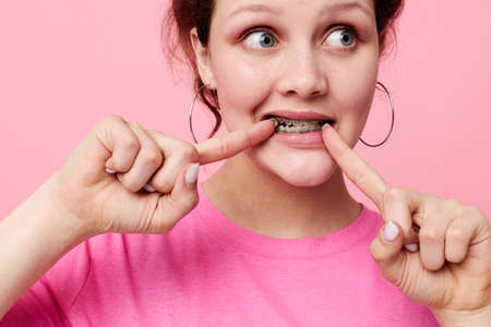 woman in pink t-shirt braces posing pink background