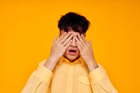 handsome man in yellow shirt posing emotions yellow backgroundの写真素材