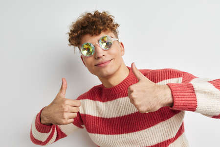 Cheerful guy with curly hair in stylish glasses posing