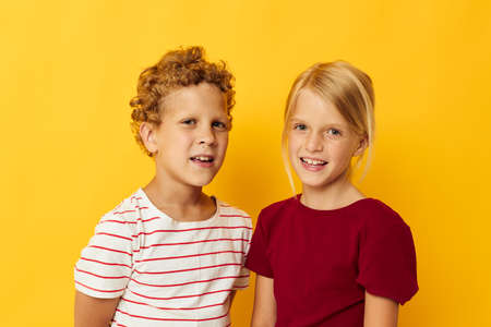 Portrait of cute children standing side by side posing childhood emotions yellow background