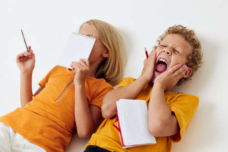 Boy and girl lie on the floor with notepads and pencils childhood lifestyle unaltered