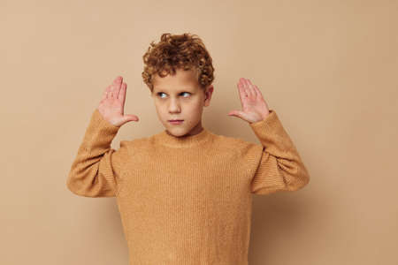 Cute little boy in a beige sweater posing fun childhood unalteredの写真素材