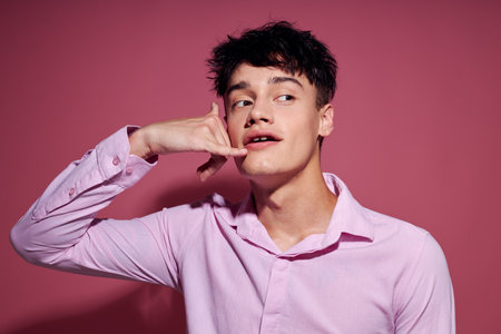 handsome guy gestures with hands emotions hairstyle fashion pink background unalteredの写真素材