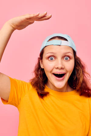 cheerful woman in a yellow t-shirt and blue cap posing emotions cropped view unalteredの写真素材