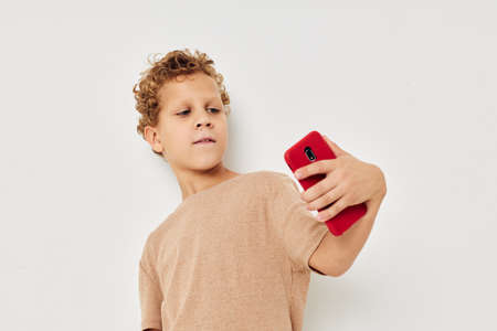 Cheerful cute boy with phone in hands posing technologyの写真素材