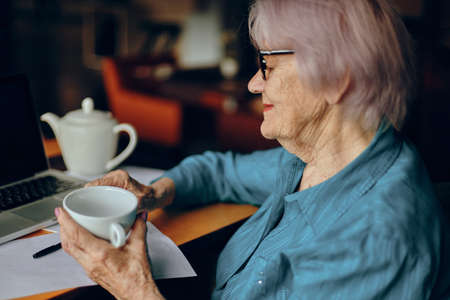 elderly woman sitting in a cafe with a cup of coffee and a laptop Lifestyle unalteredの写真素材