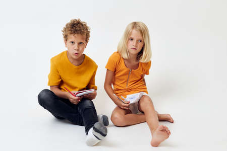 two joyful children drawing fun games with notepad childhood lifestyle unalteredの写真素材