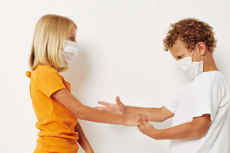 Small children fun medical mask stand side by side close-up lifestyle unaltered