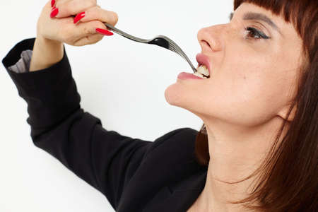 beautiful woman in a black jacket a knife and a fork near the face Lifestyle unalteredの写真素材