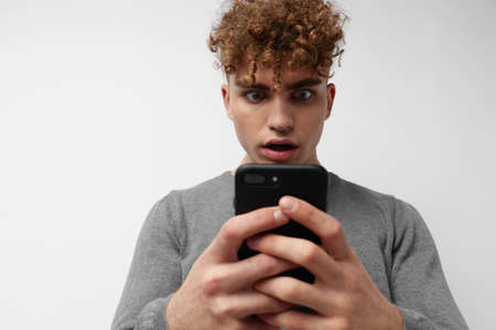 Attractive man talking on the phone posing emotions light backgroundの写真素材