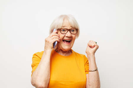 Portrait of an old friendly woman happy lifestyle in yellow t-shirts isolated backgroundの写真素材