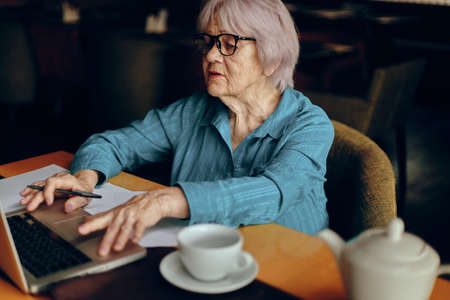 A businesswoman sitting in a cafe with a cup of coffee and a laptop Freelancer works unalteredの写真素材