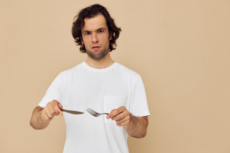 man in a white T-shirt with knife with fork isolated backgroundの写真素材