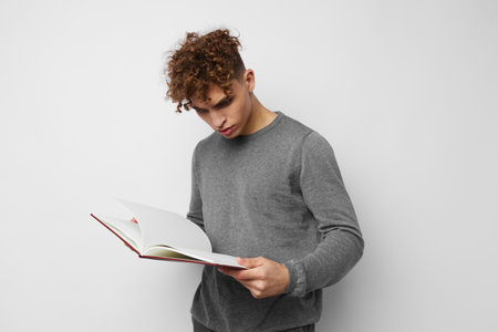 cute guy with curly hair with a book in his hands trainingの写真素材