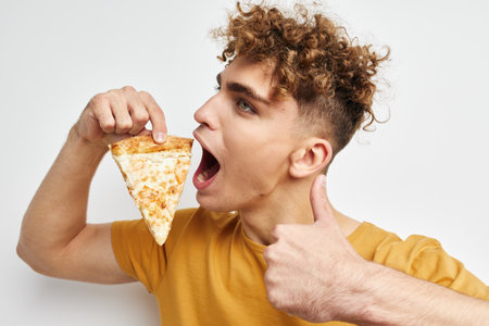 kinky guy in a yellow t-shirt eating pizza Lifestyle unalteredの写真素材