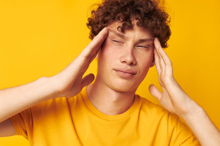 Young curly-haired man Youth style studio casual wear yellow background unalteredの写真素材