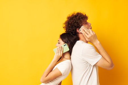 a guy with a girl in white t-shirts talking on the phone yellow background