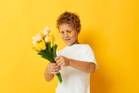 Photo portrait curly little boy with yellow flowers posing childhood fun isolated background...