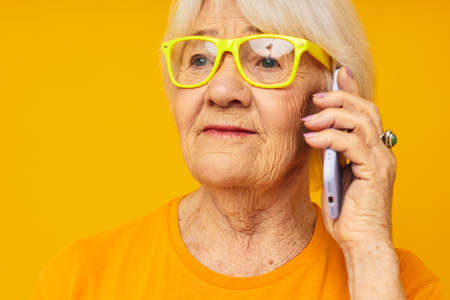smiling elderly woman in casual t-shirt communication by phone close-up emotions
