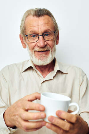 old man in glasses with a mug on a white background joyful